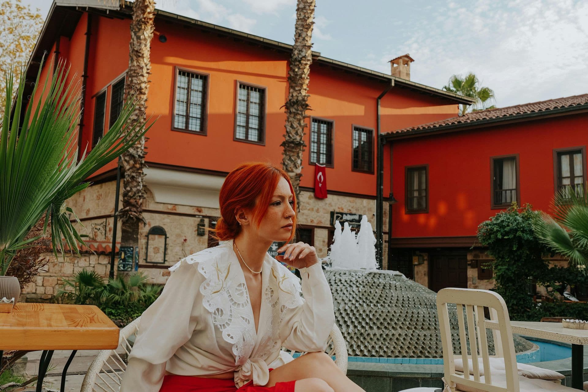Palm trees and a woman seated in a historic courtyard in Antalya's old town.