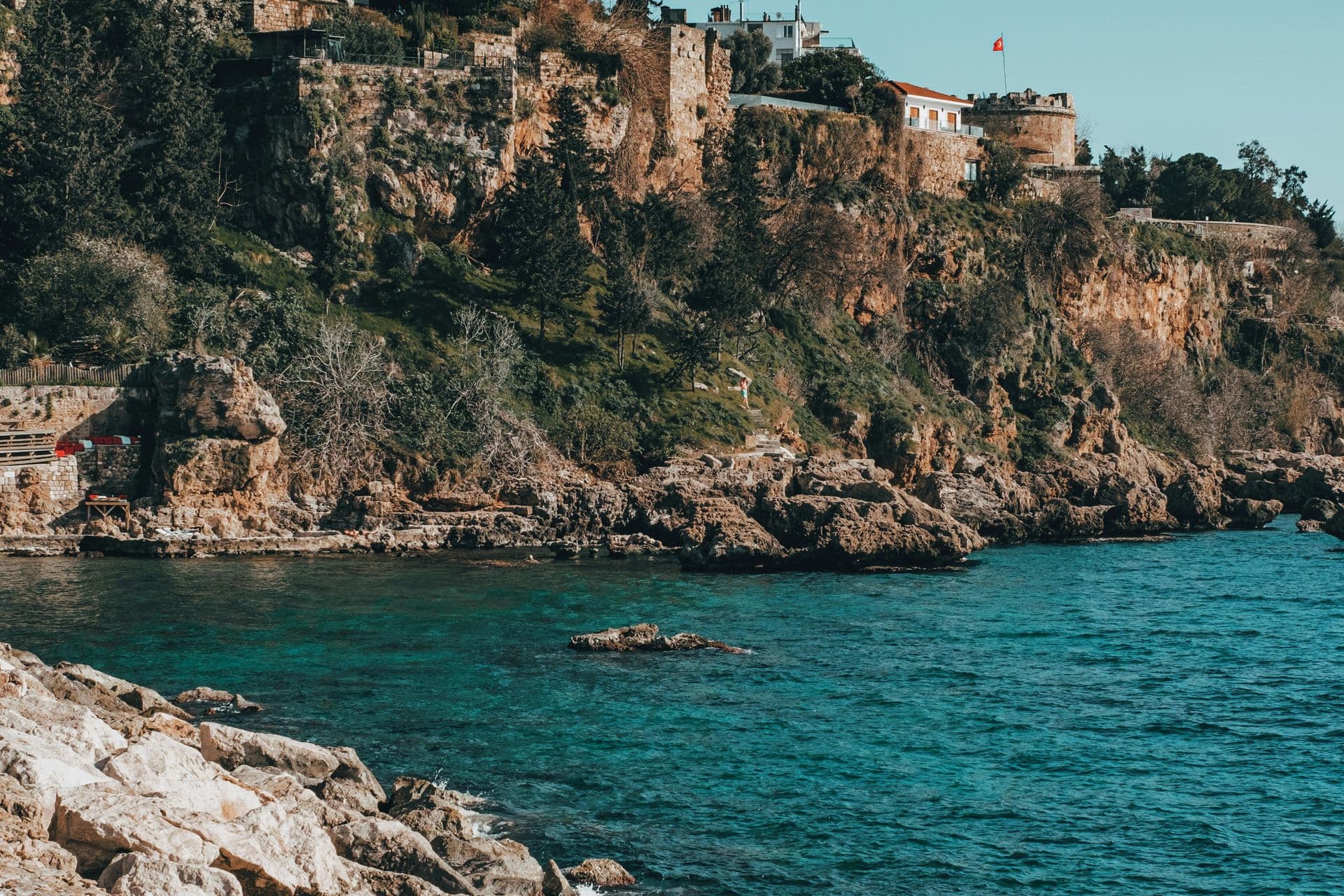 Historic stone walls and crystal-clear sea view in Antalya's old town.