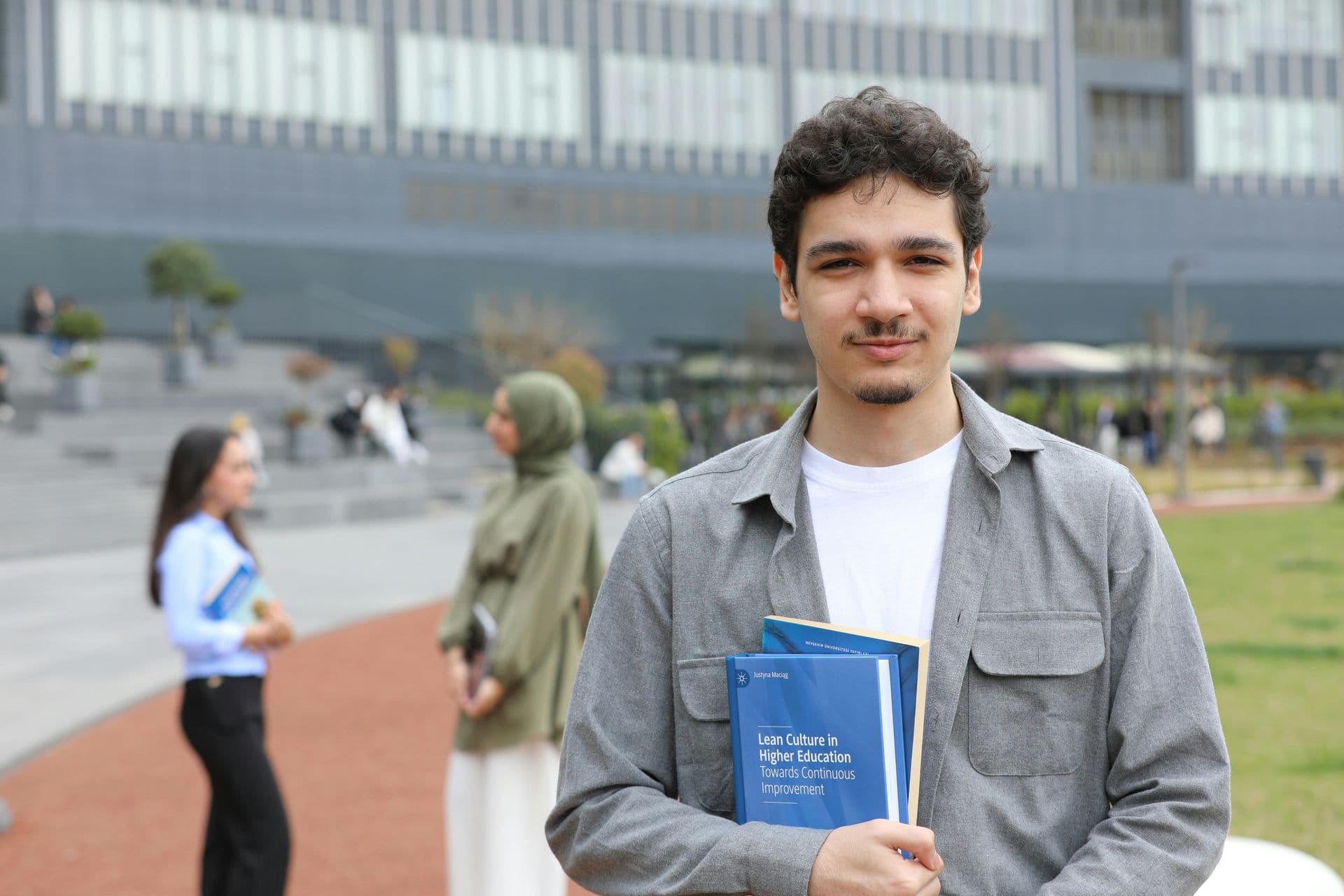 International student holding a book on a university campus.